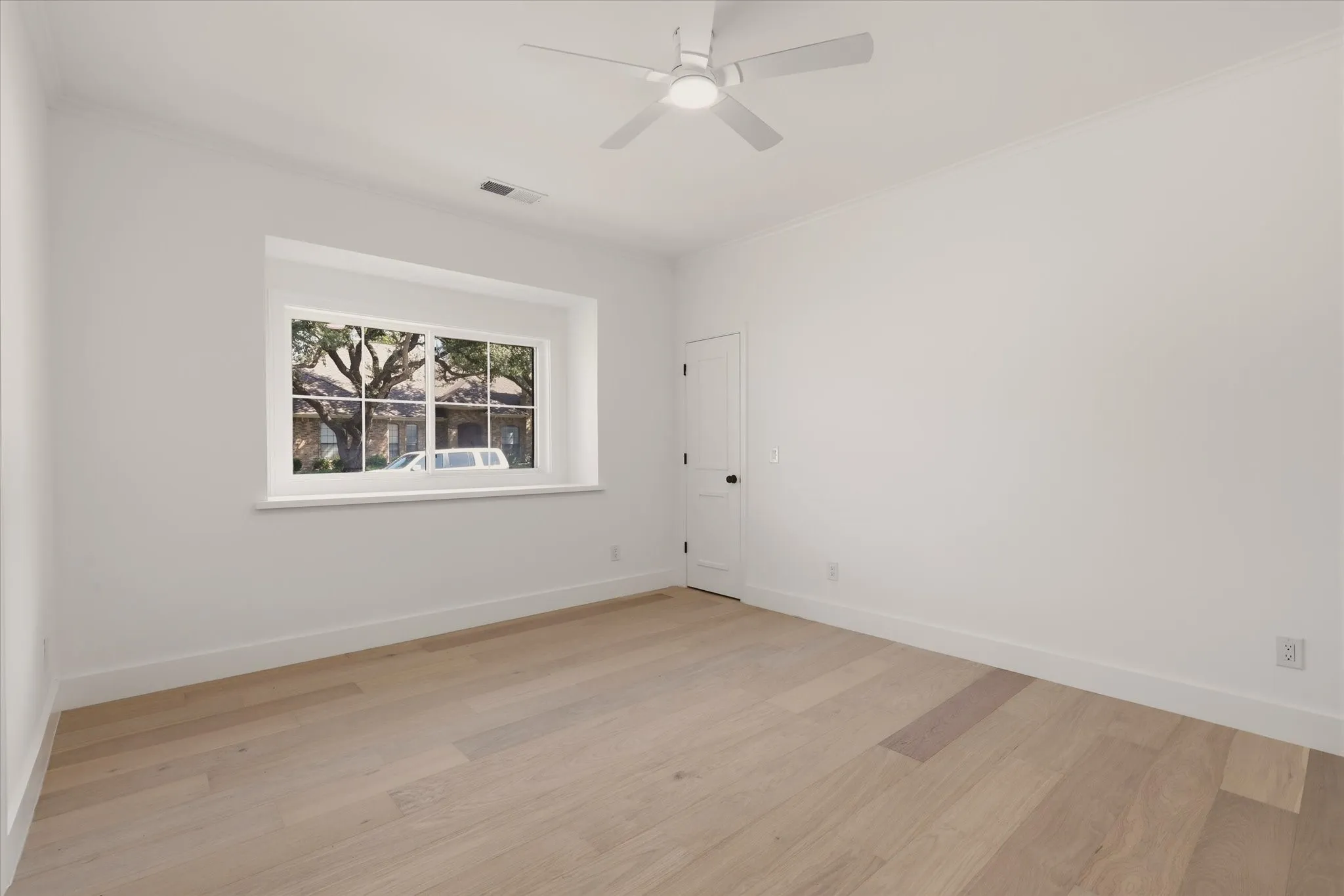 Recessed window with white trim, light wood-finish flooring, white walls, ceiling fan with integrated lighting, and crown molding