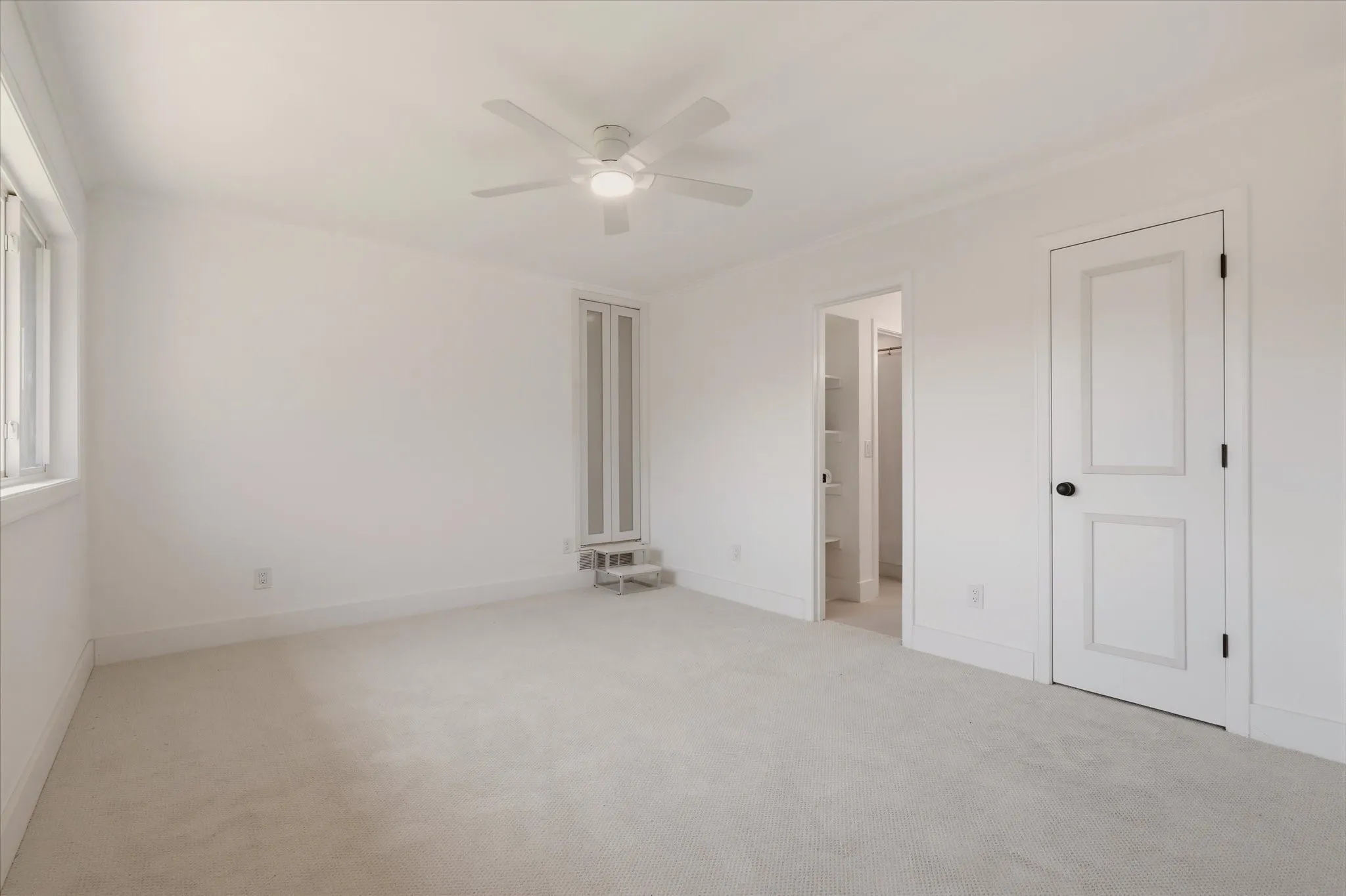 Wall-to-wall carpeting, white painted walls, a built-in ceiling fan with integrated lighting, and multiple paneled doors