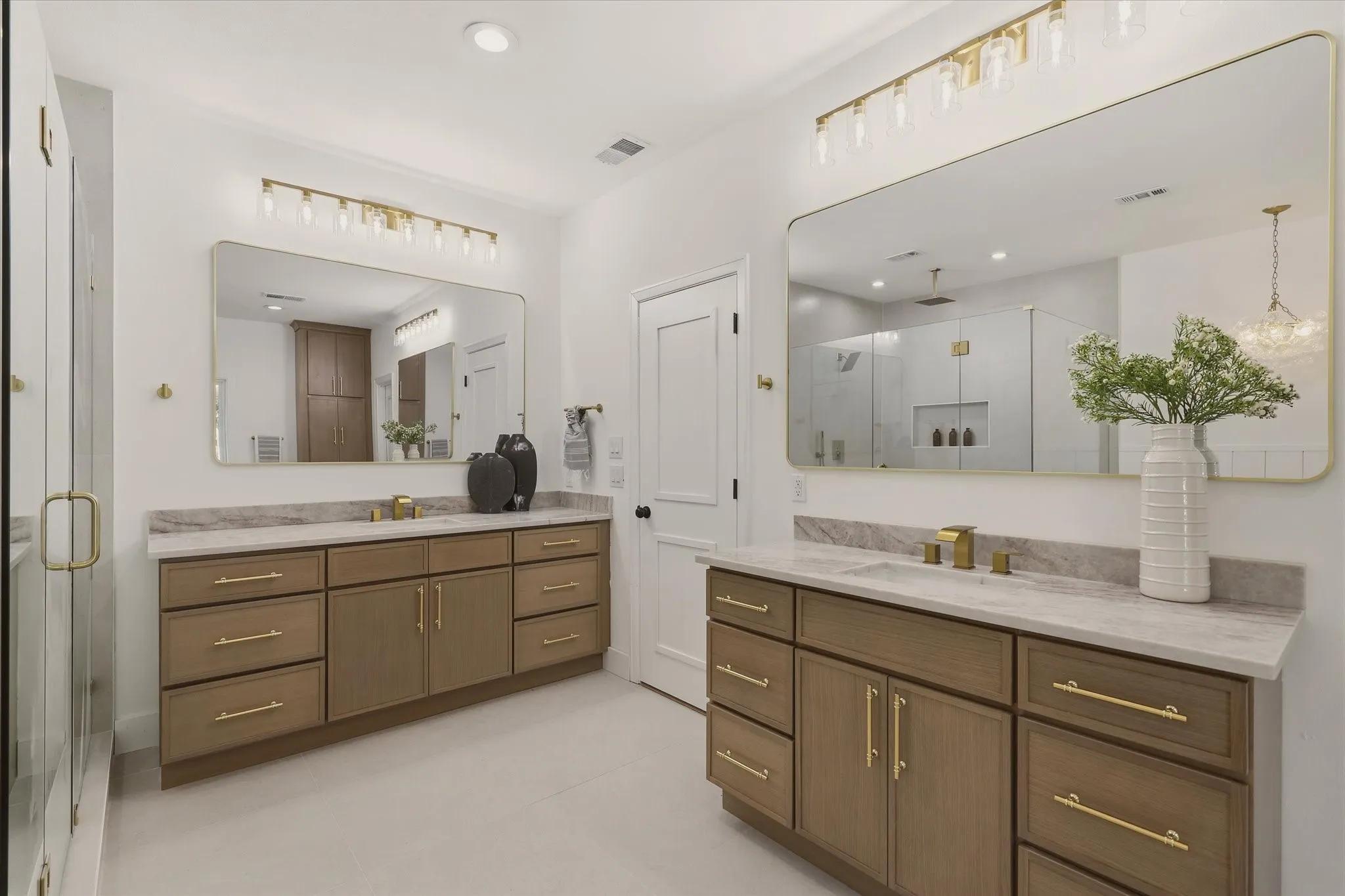 Dual vanity featuring wood-finish cabinetry and gold-tone hardware
