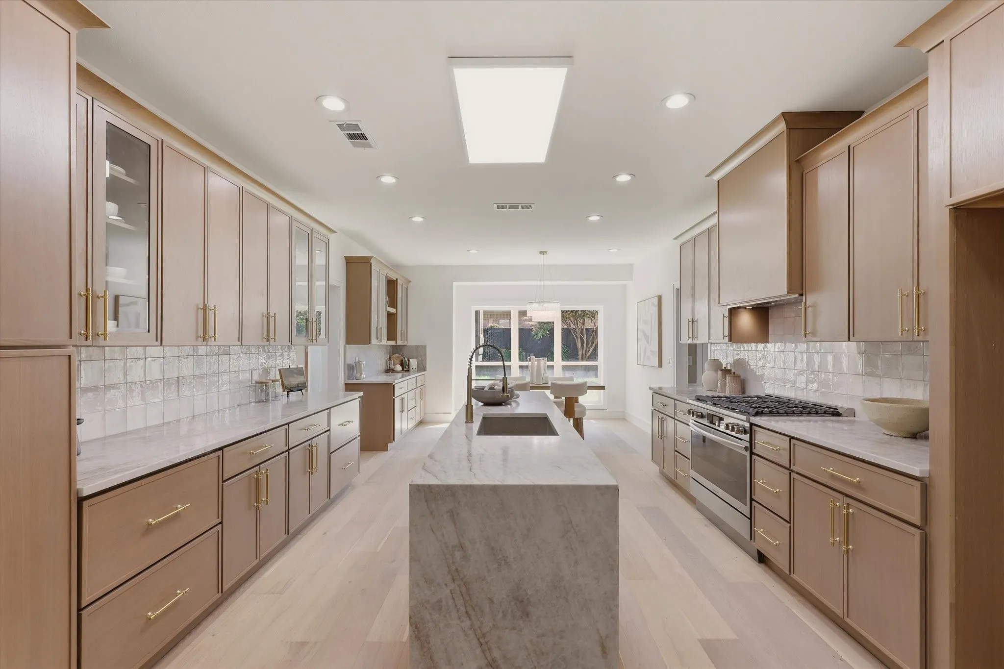 Kitchen featuring wood-finish cabinetry, stone countertops, a large center island with an integrated sink, a stainless steel range, and recessed lighting