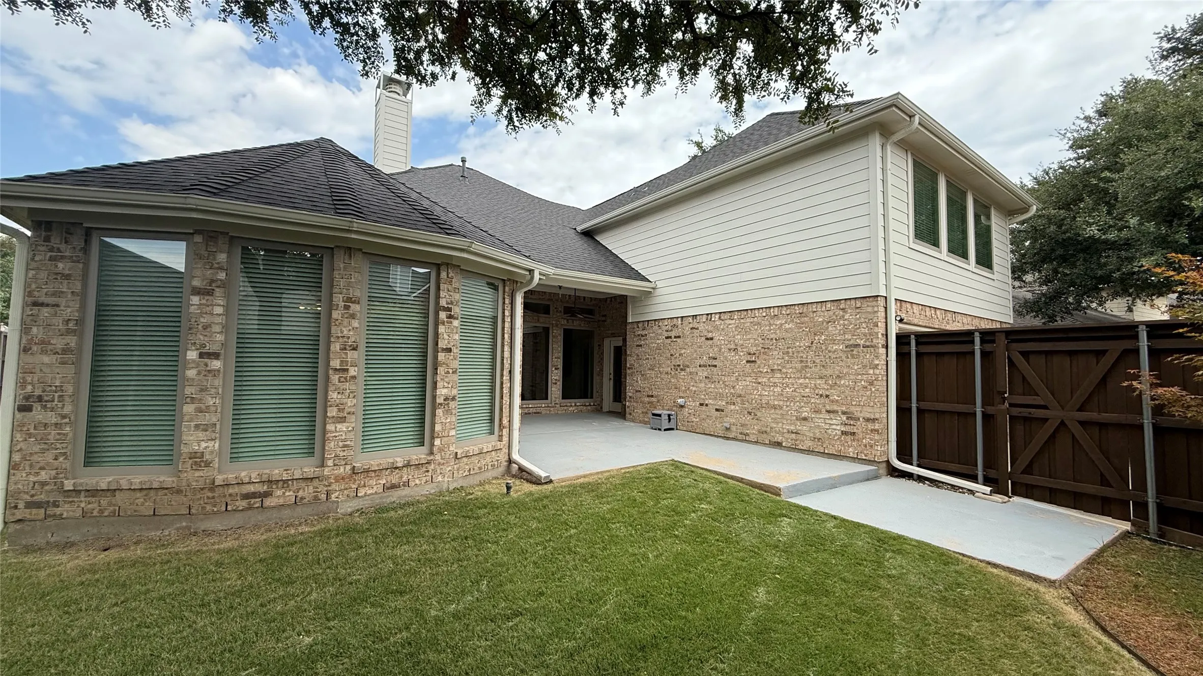 Brick and siding exterior with a dark shingle roof