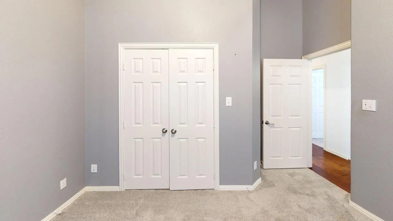 Neutral-toned walls, plush carpet flooring, white paneled doors, and white trim accents
