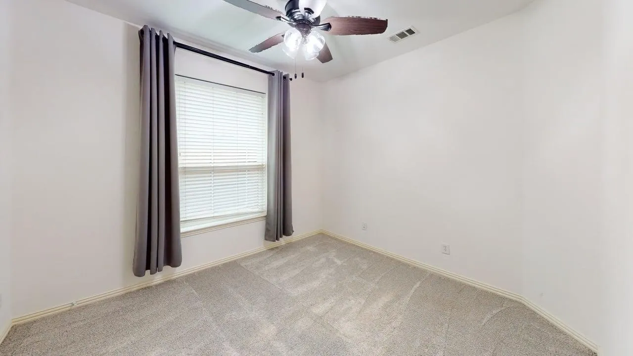 Neutral-toned wall-to-wall carpeting, window with blinds, and ceiling fan with integrated lighting