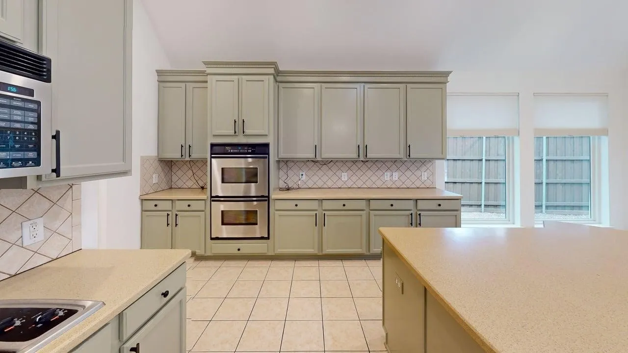 Kitchen featuring extensive cabinetry, tile flooring, light-toned countertops, and stainless steel double ovens