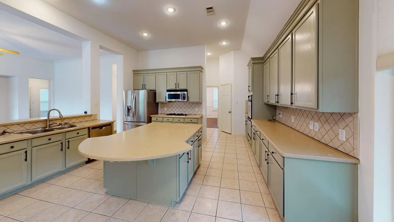Kitchen featuring a curved island, tile flooring, recessed lighting, and ample cabinetry with black hardware