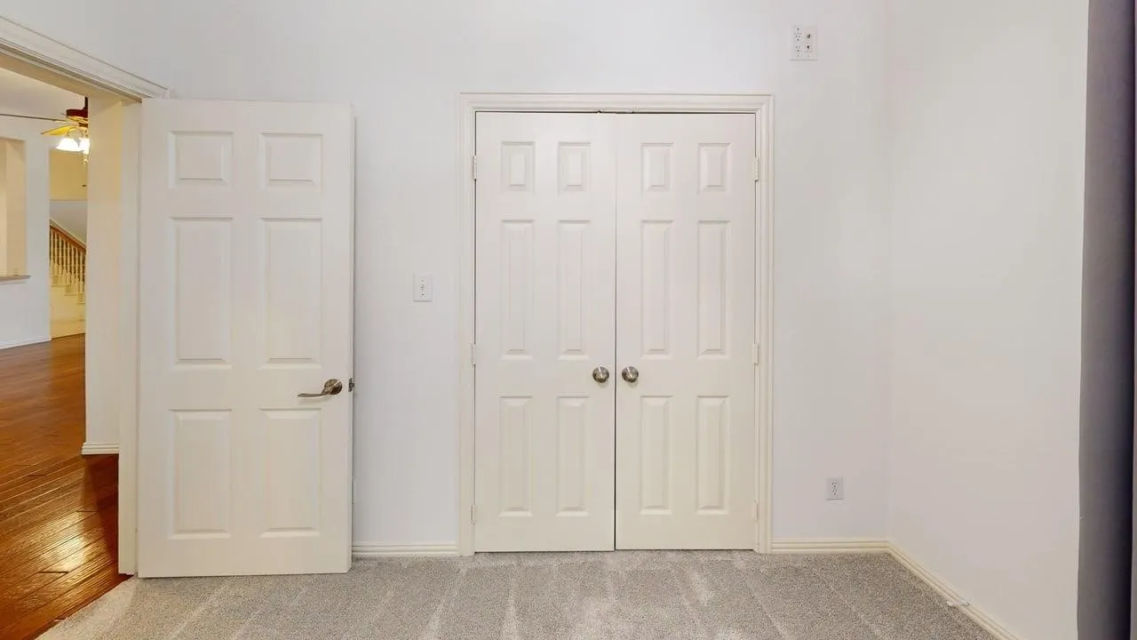 Light gray carpeting, white painted walls, white paneled doors, and brushed nickel hardware