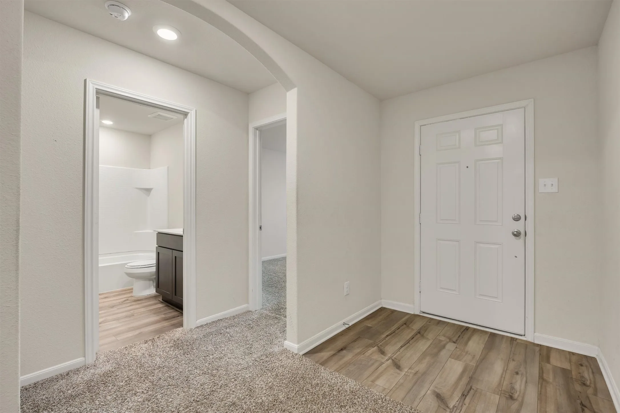 Entry with wood-finish flooring, recessed lighting, and an arched doorway