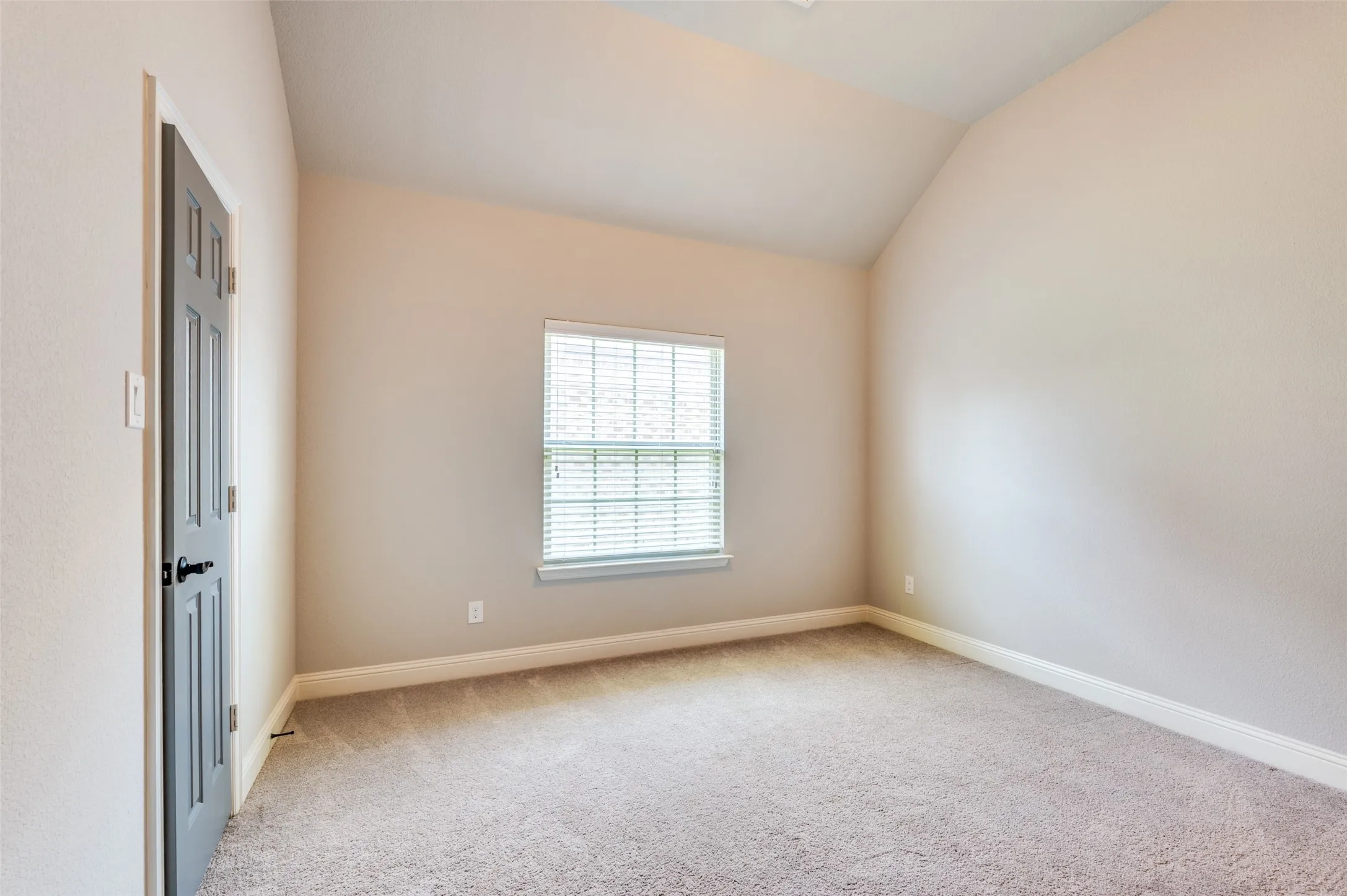 Vaulted ceiling, neutral paint, light gray carpeting, window with blinds, and white trim