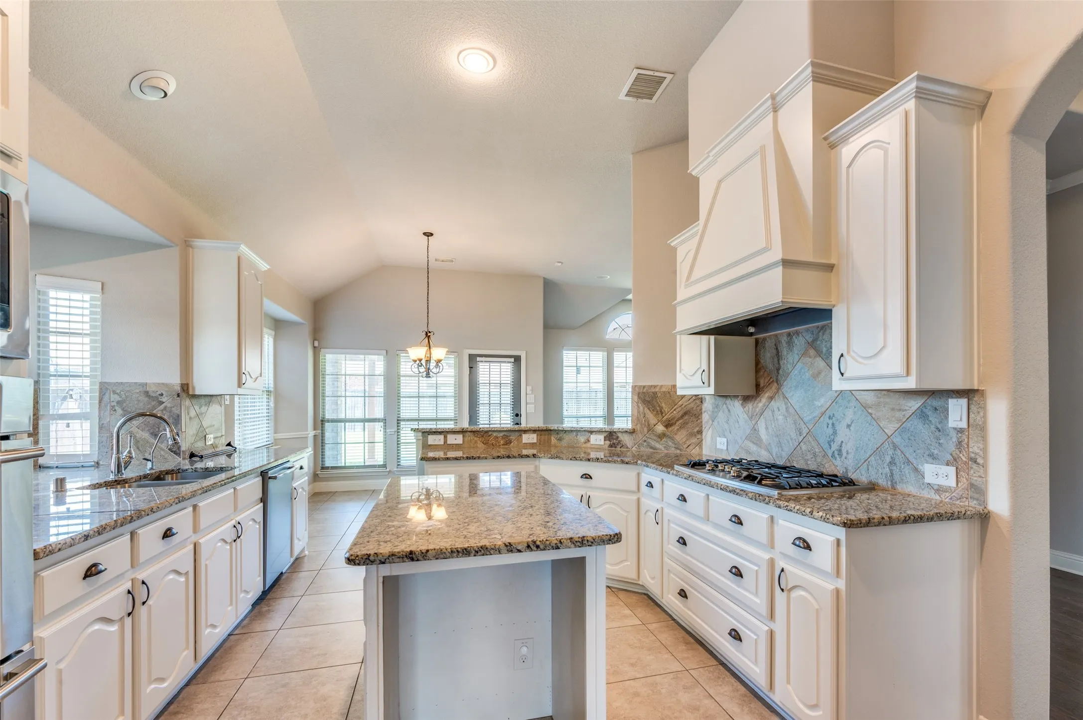Expansive kitchen featuring granite countertops, white cabinetry, a tiled backsplash, a kitchen island, and recessed lighting