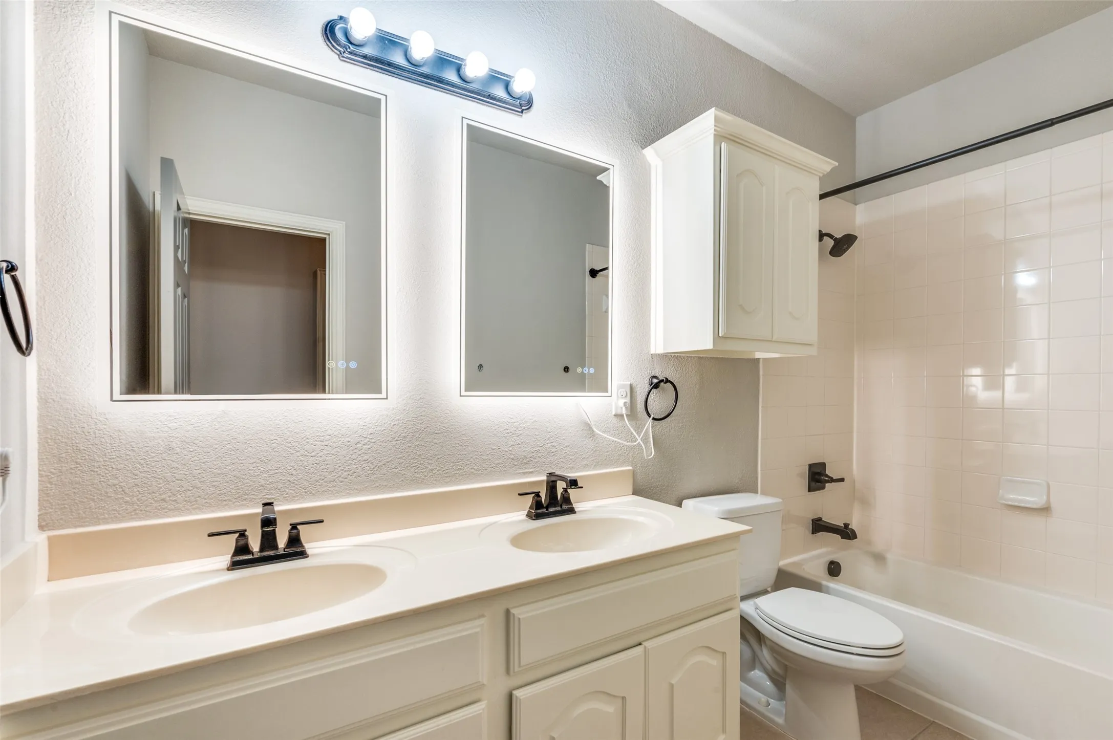 Dual vanity with integrated sinks, back-lit mirrors, and matte black fixtures