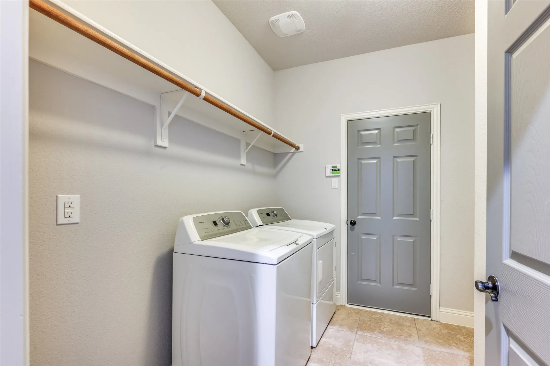 Utility room featuring tile flooring, built-in shelving, and a paneled door