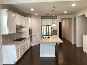 Kitchen featuring white cabinetry, stainless steel appliances, a center island with sink, dark wood-finish flooring, and recessed lighting