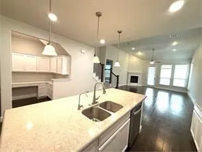 Kitchen island with integrated double sink, stainless steel dishwasher, and pendant lighting