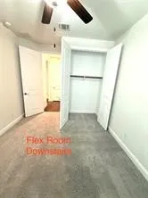 Neutral wall palette, ceiling fan with wood-finish blades, soft carpeting, and a built-in closet with hanging rod