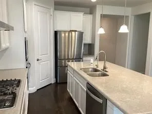 Kitchen featuring a gas cooktop, double basin sink, stainless steel appliances, and pendant lighting