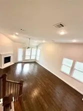 Wood-finish flooring, recessed lighting, and a corner fireplace with a white mantel