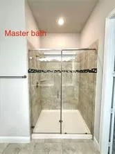 Glass-enclosed shower with tiled walls and a built-in shelf