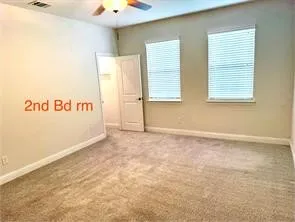 Carpeted room with two windows, a ceiling fan, and a single door