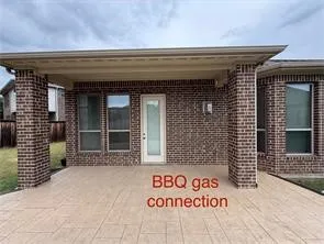 Covered patio with brick columns, stamped concrete flooring, exterior lighting, and a BBQ gas connection