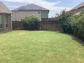 Expansive backyard featuring a manicured lawn, established privacy fencing, and mature shrubbery