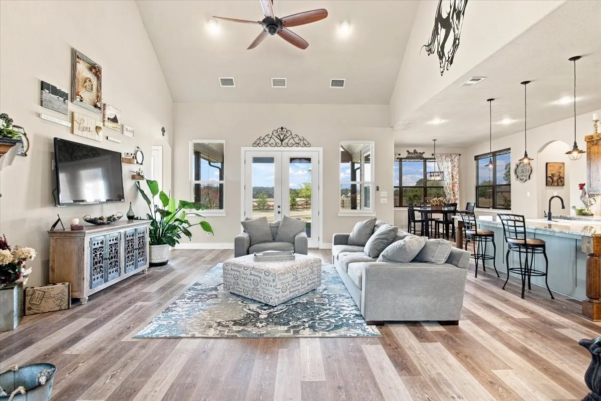 Vaulted ceiling, wood-finish flooring, French doors, recessed lighting, and a ceiling fan