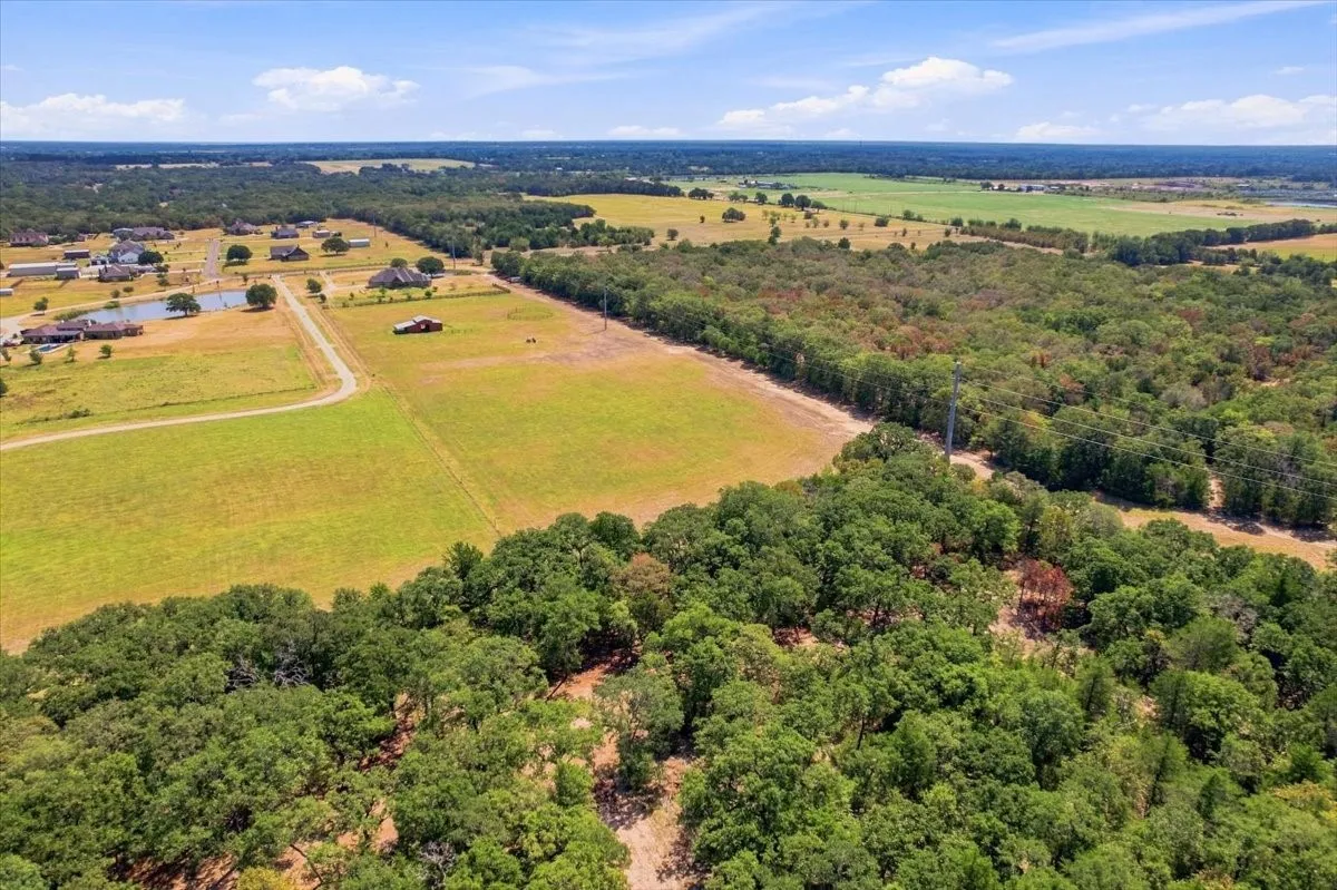 Expansive acreage featuring mature trees, open fields, and residential development