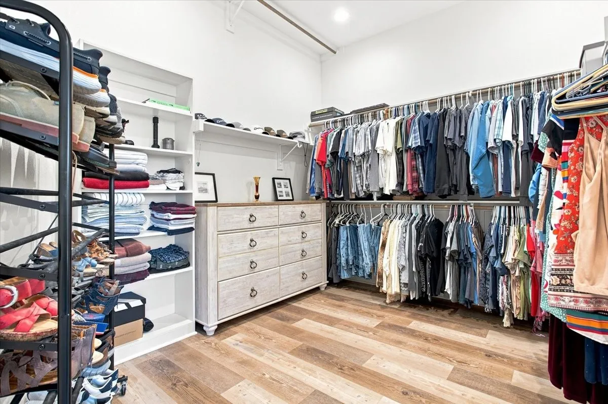 Built-in shelving, wood-finish flooring, recessed lighting, and a multi-drawer dresser