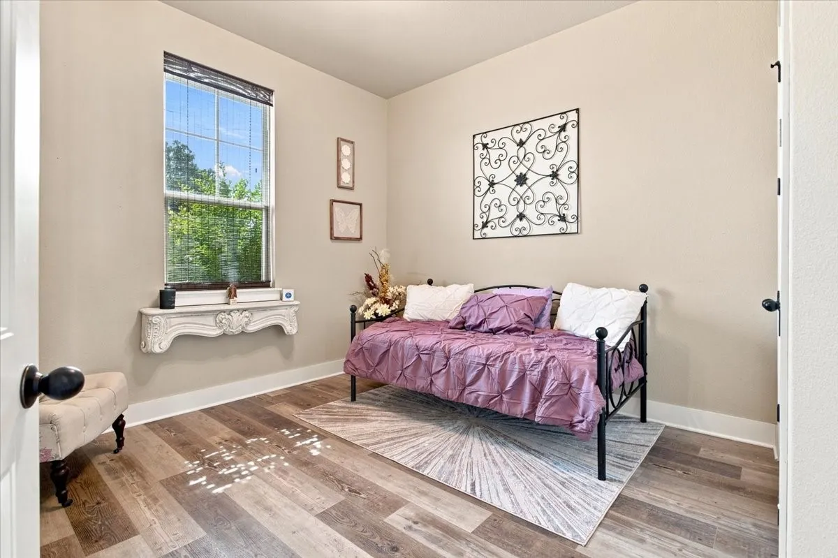 Wood-finish flooring, a tall window with horizontal blinds, and a decorative wall shelf