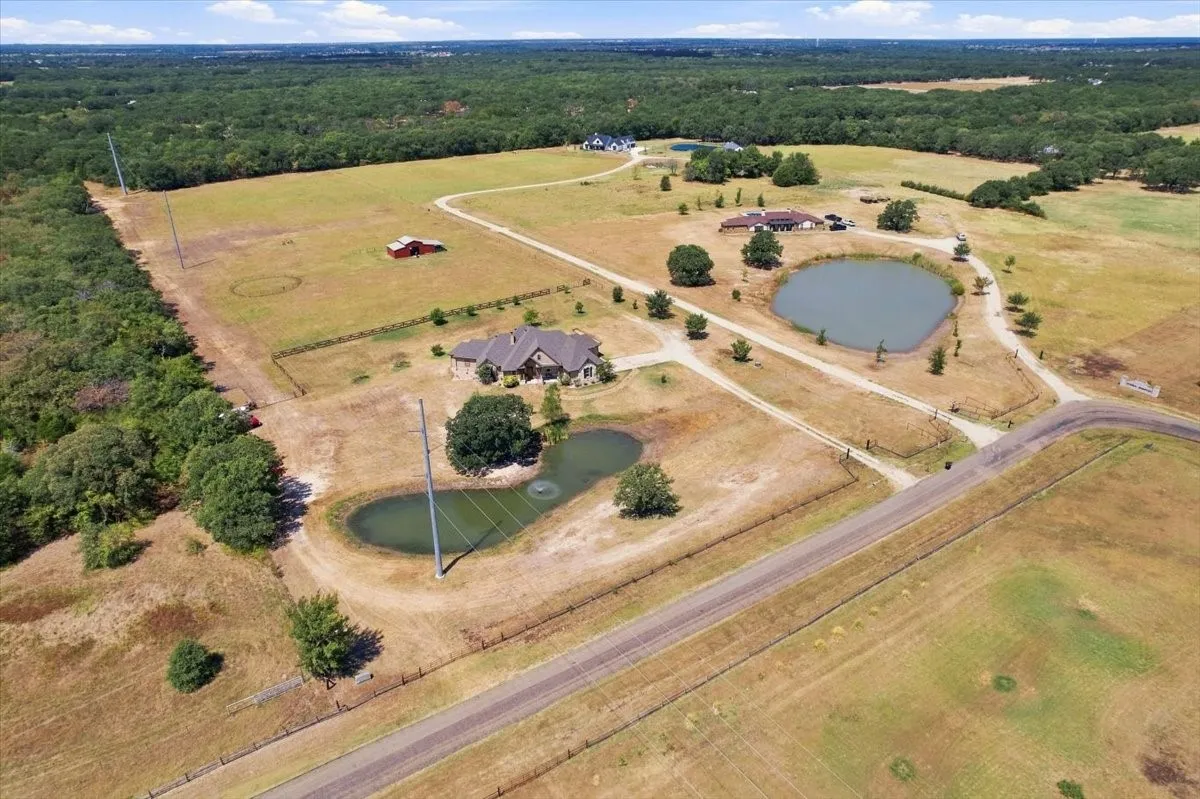 Expansive property featuring a primary residence, two ponds, a red barn, and established trees