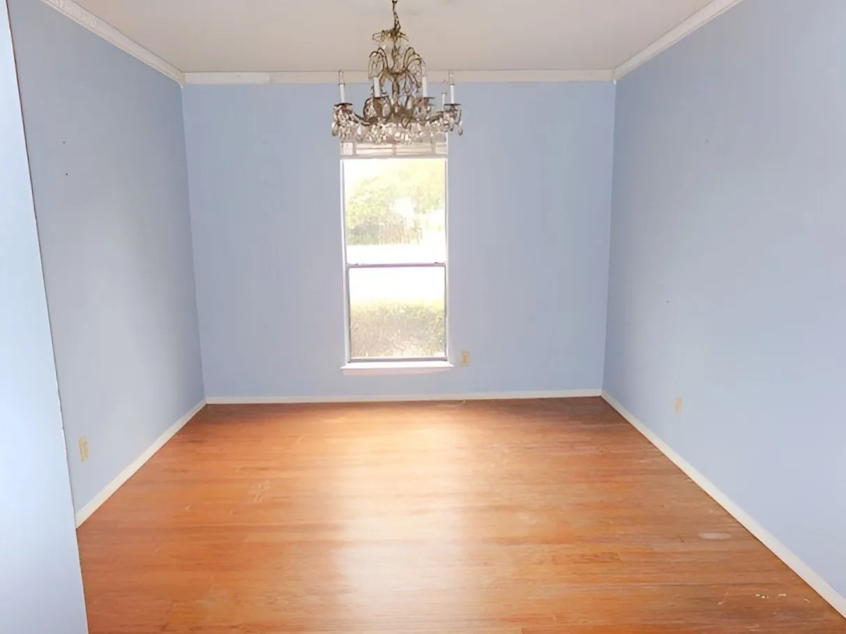 Formal DIning room Wood-finish flooring with light blue wall color, crown molding, and a central chandelier