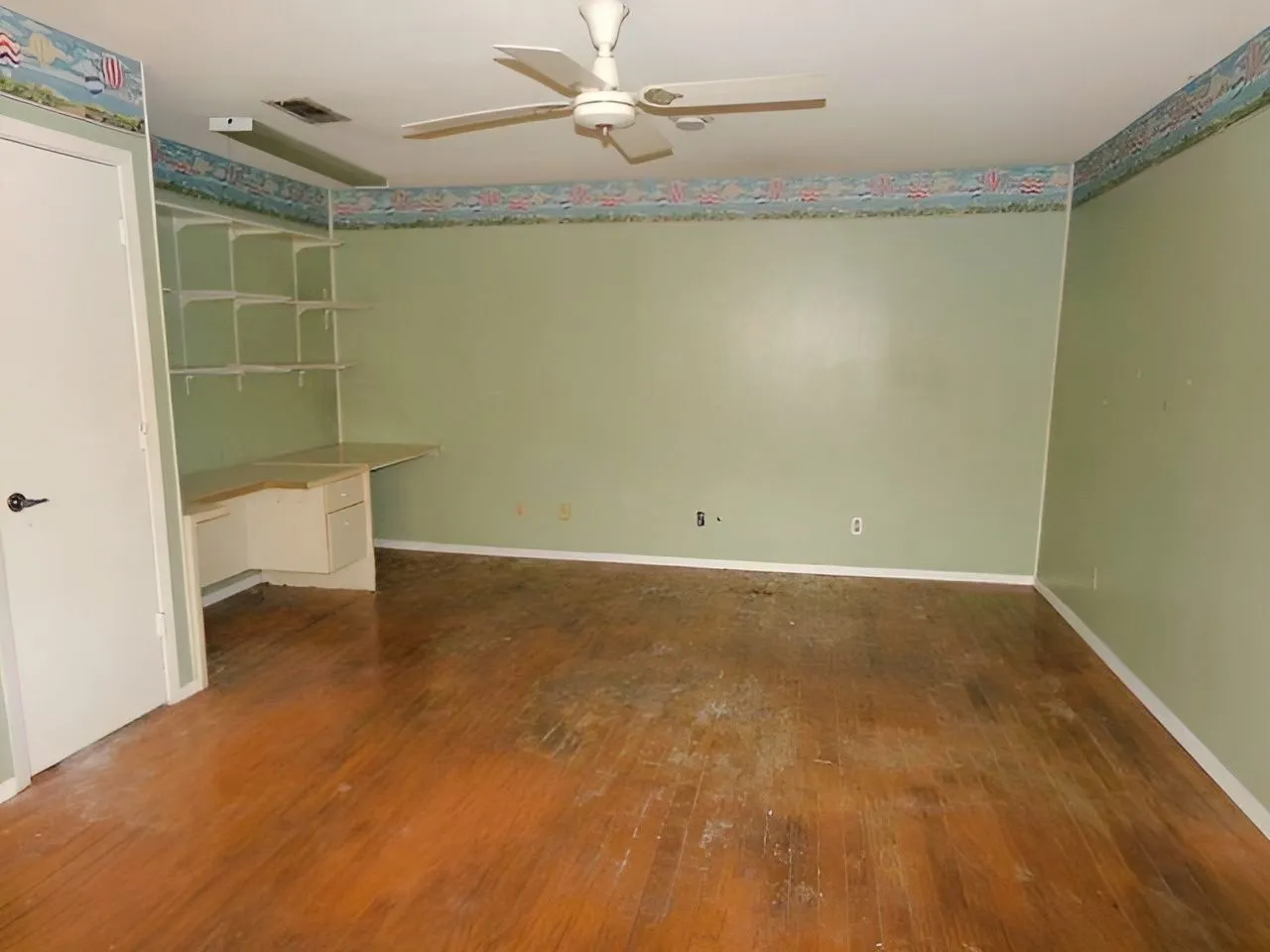 Built-in desk with shelving, wood-finish flooring, ceiling fan, and wall-mounted light fixture
