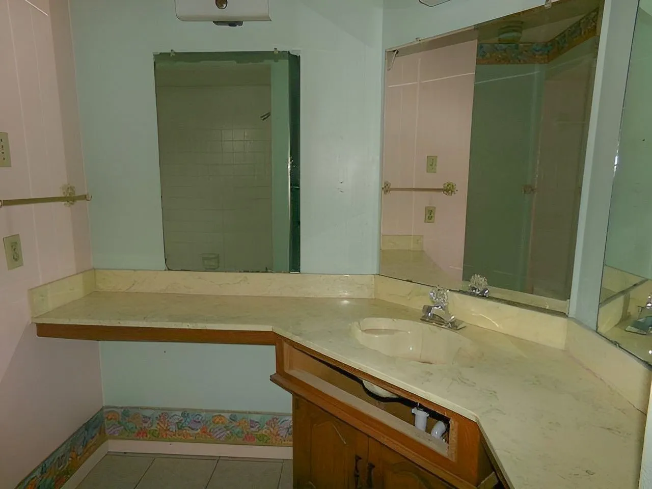 Built-in vanity with integrated sink, expansive countertop space, wall-mounted mirror, and tile flooring