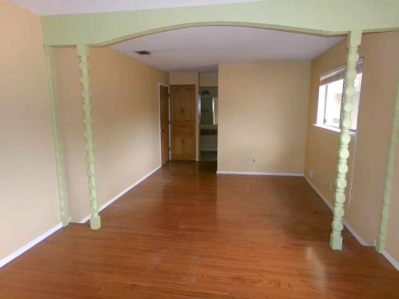 Wood-finish flooring throughout, framed by a decorative archway with carved pillars