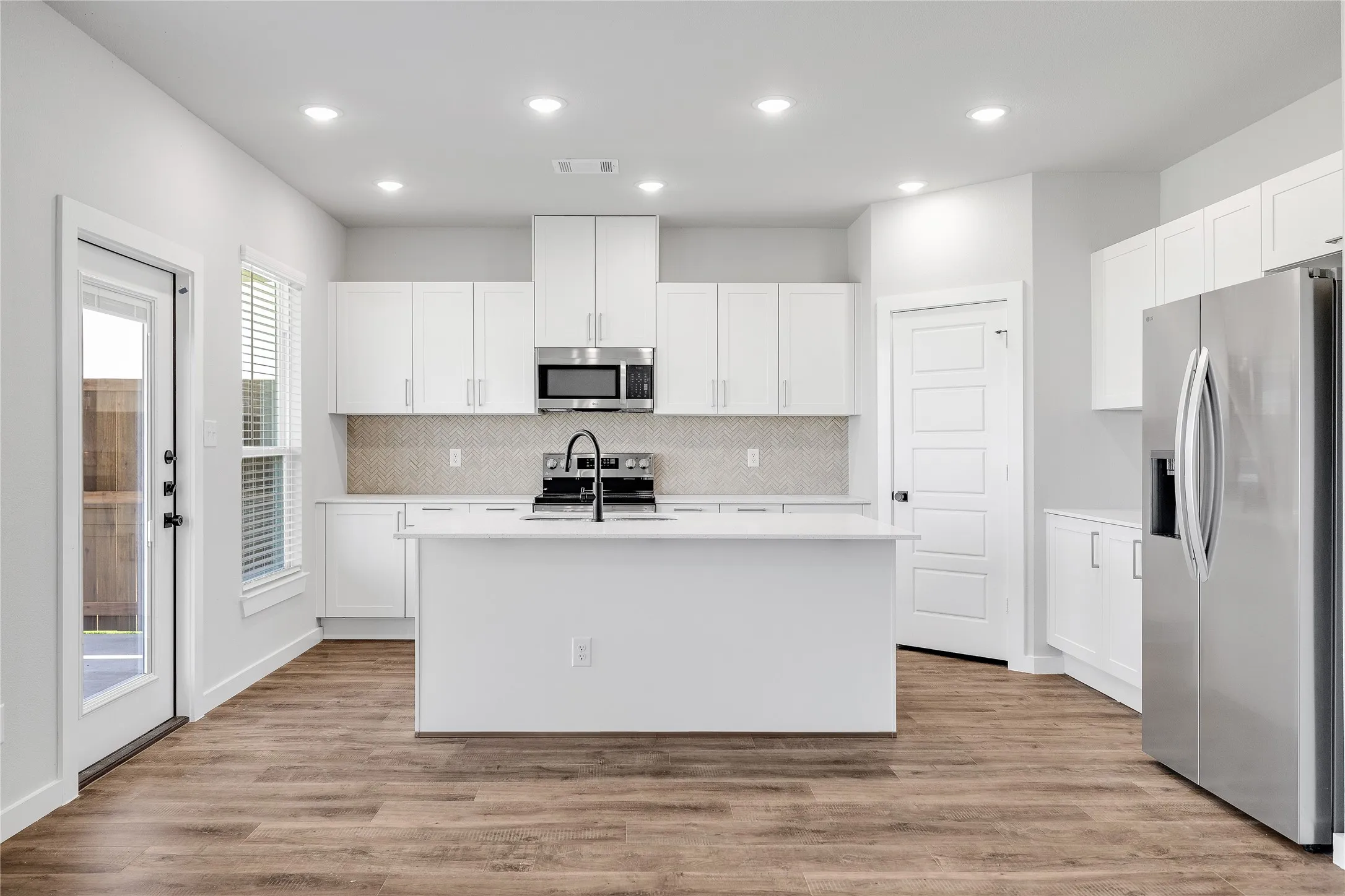 Contemporary kitchen with white cabinetry, stainless steel appliances, and wood-finish flooring