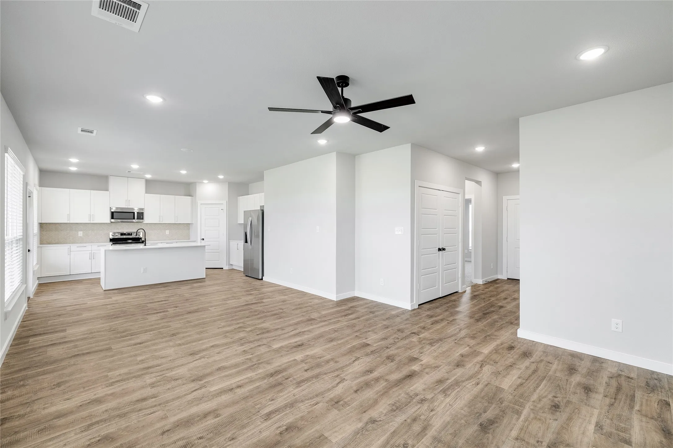 Open-concept living space featuring wood-finish flooring, recessed lighting, and a black ceiling fan