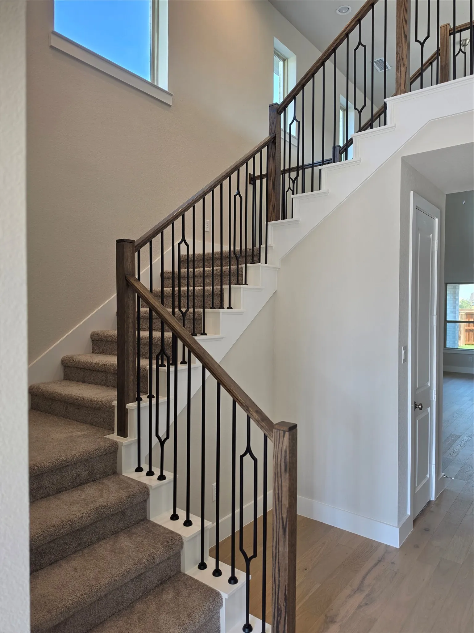 Carpeted staircase with white risers and dark wood-finish handrails