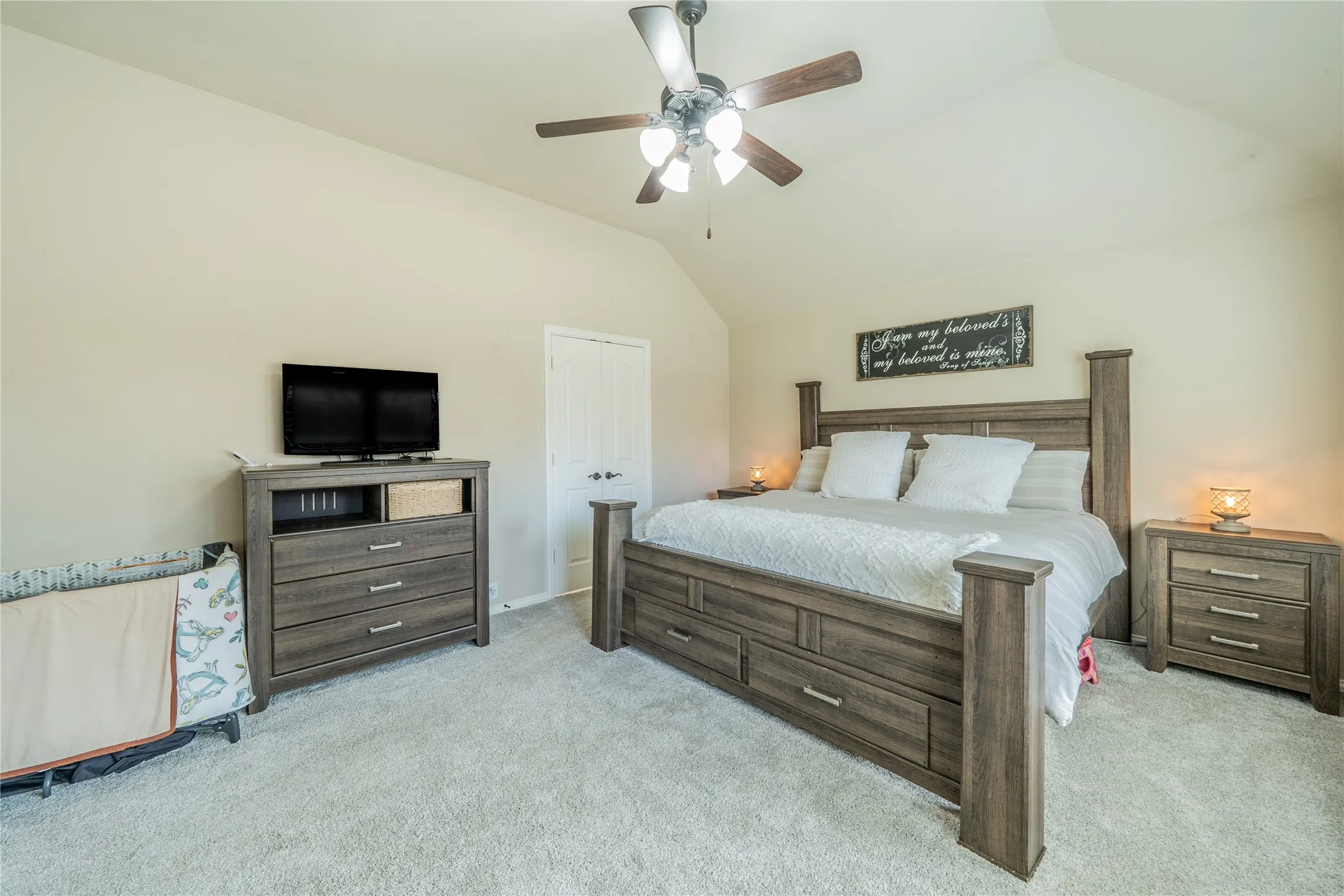 Vaulted ceiling with a ceiling fan, light neutral wall paint, and light-toned carpeting