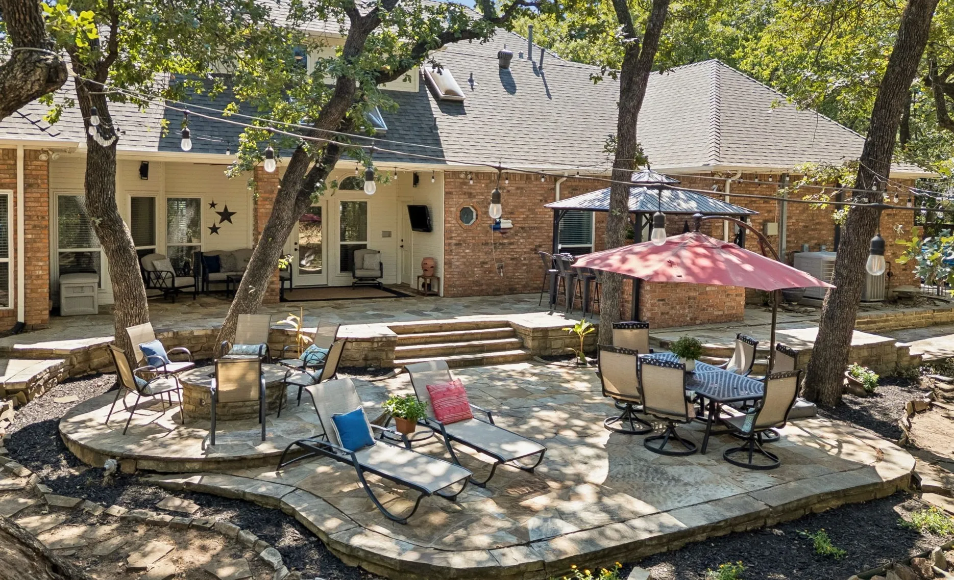 Backyard features firepit, seating areas, dining space and pergola with outdoor kitchen.
