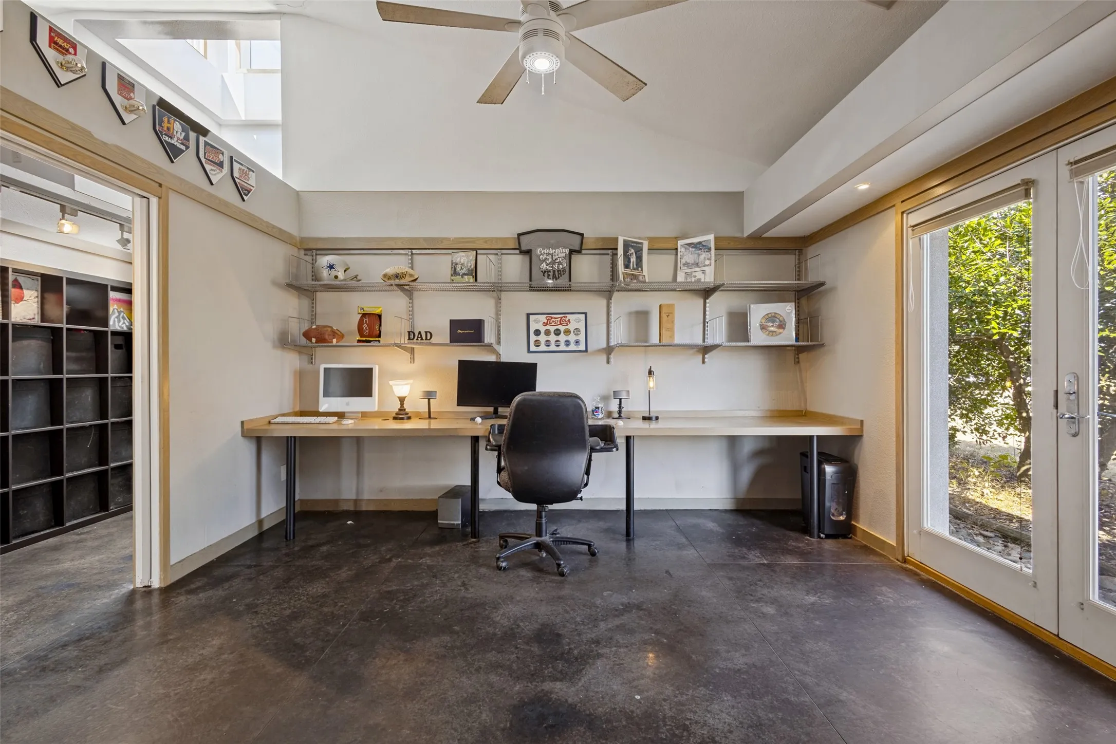 Pocket doors open to the room.  Stained concrete is on the floor and a ceiling fan is above.  One wall is open above to the hallway.