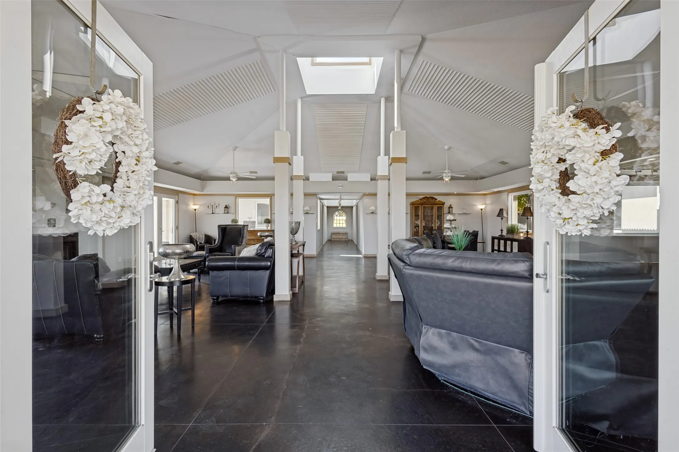 Guests are welcomed inside and greeted by a huge open gathering space which can be divided into separate areas to fit lifestyle choices.  Seating, dining, media, a pool table or music nook are all possible in this area.  A tall ceiling vaults up to a skylight which fills the room with light.  French doors and windows open the room to the outdoors.
