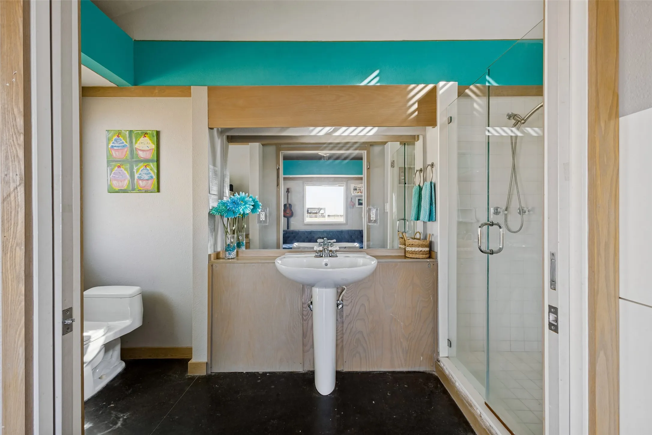 The attached bath in this suite matches the decor in the bedroom with the same flooring and the turquoise accent paint color.  The bathroom has a pedestal sink and shower with pocket doors that close the room.