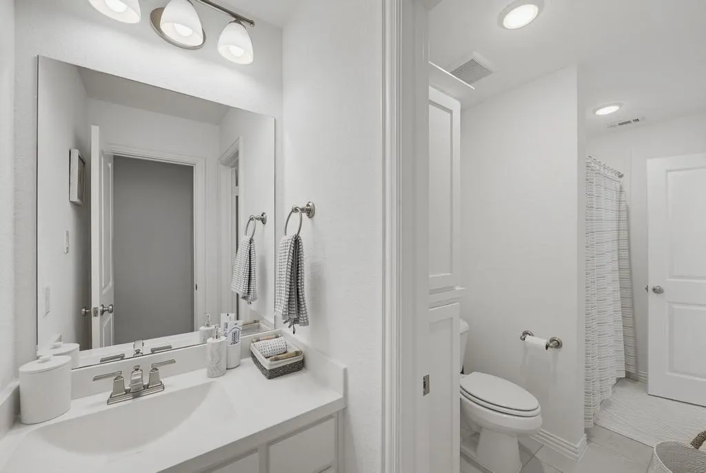 Vanity with integrated sink, brushed nickel faucet, large wall mirror, and overhead vanity lighting