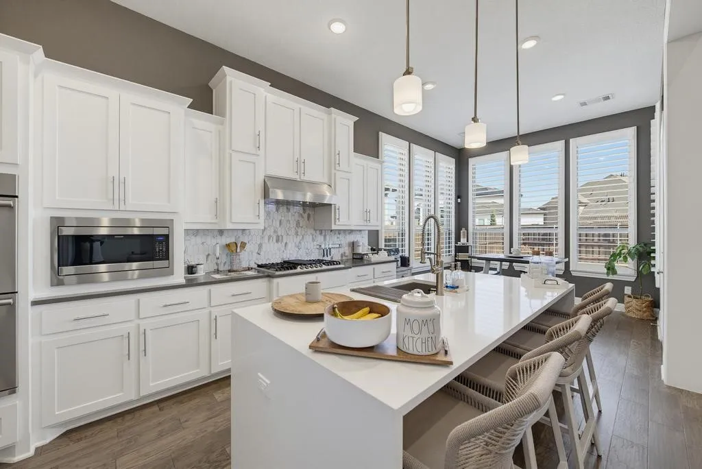 Gourmet kitchen with white cabinetry, stainless steel appliances, a large center island, and wood-finish flooring