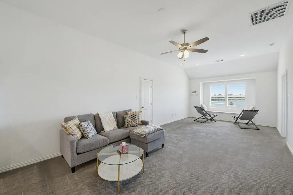 Spacious room with sloped ceiling, recessed lighting, ceiling fan, and a built-in window seat