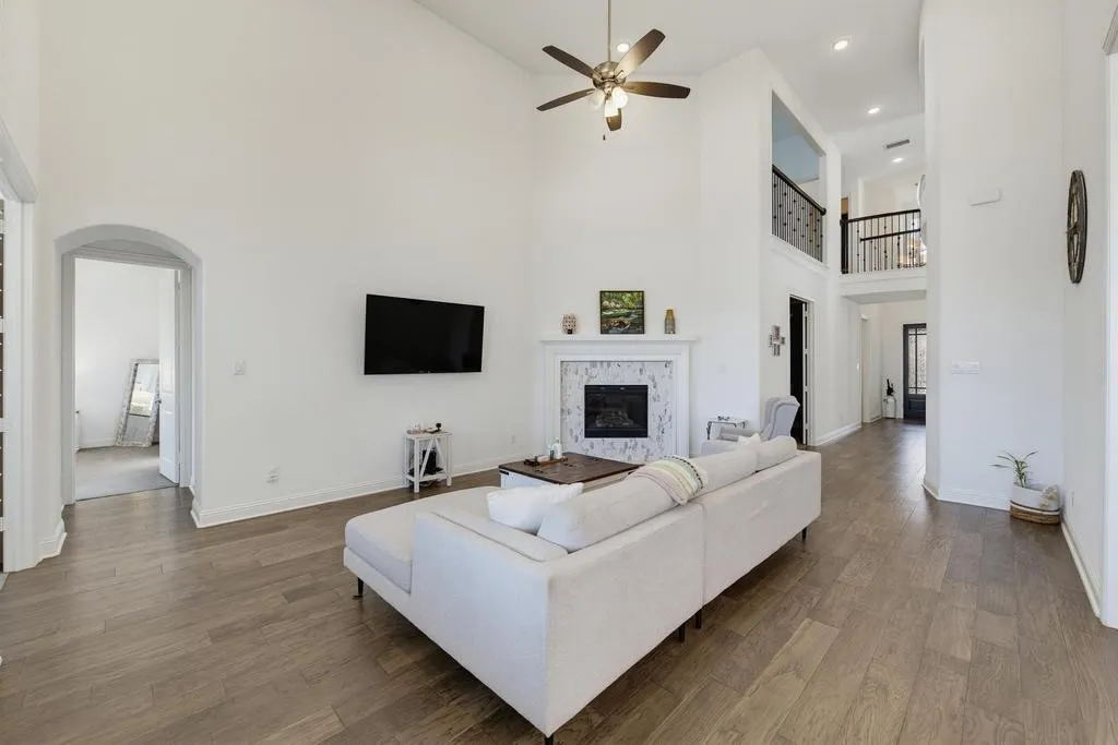 Vaulted ceilings, wood-finish flooring, fireplace with tile surround, and an upper-level overlook with wrought iron railing