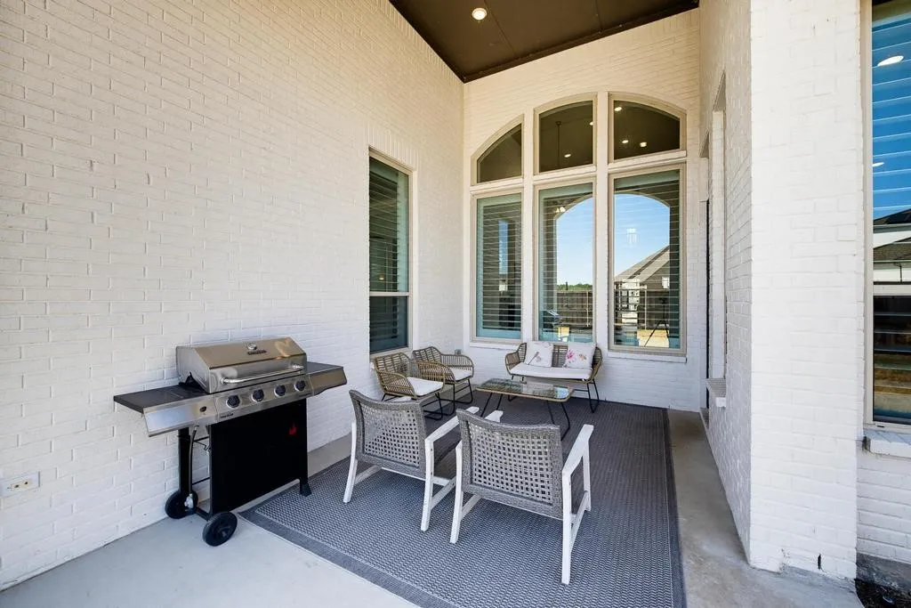Covered patio with white brick exterior, arched transom window, and concrete flooring