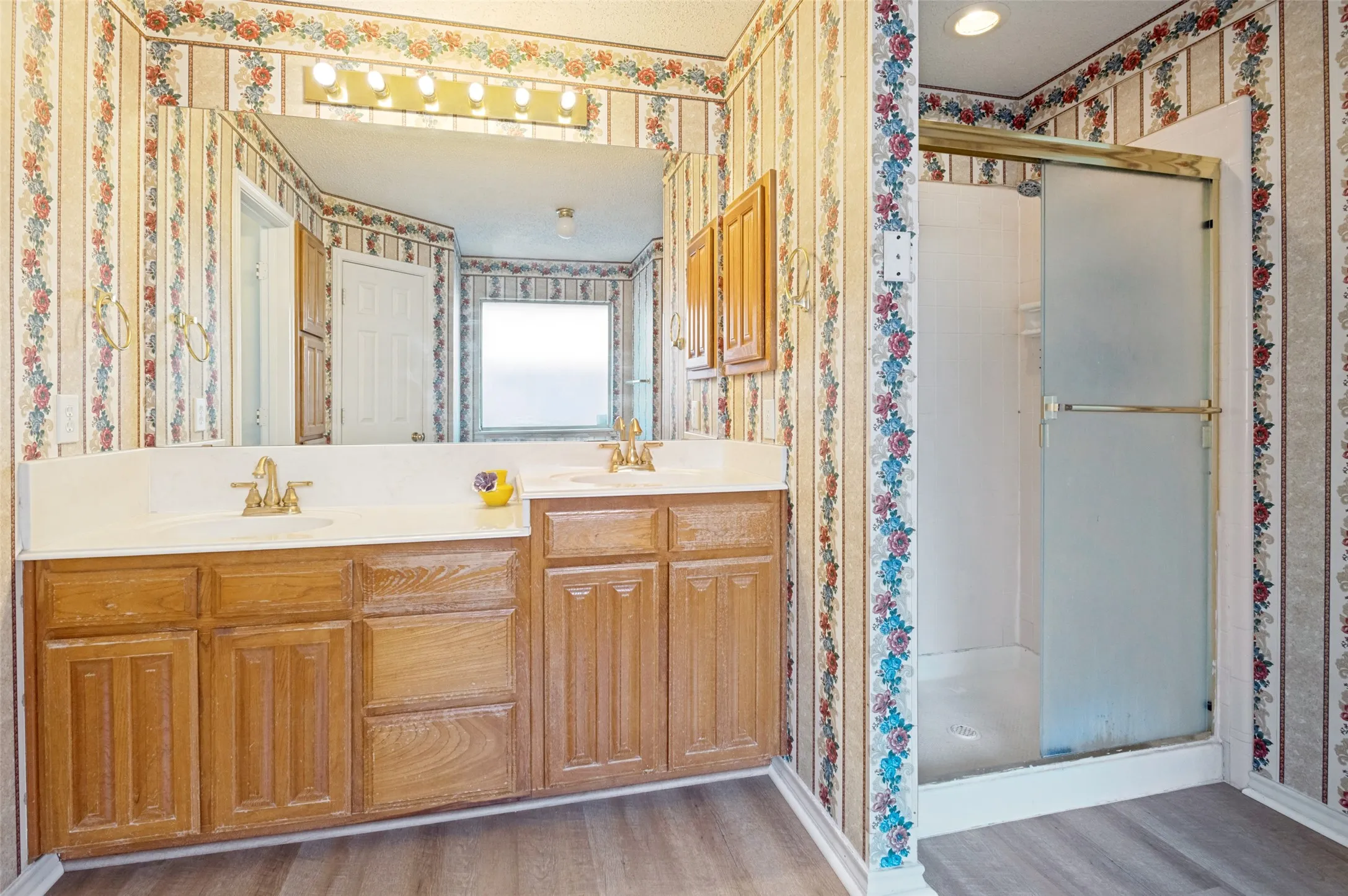 Dual vanity with brass-finish faucets, wood cabinetry, and a framed mirror