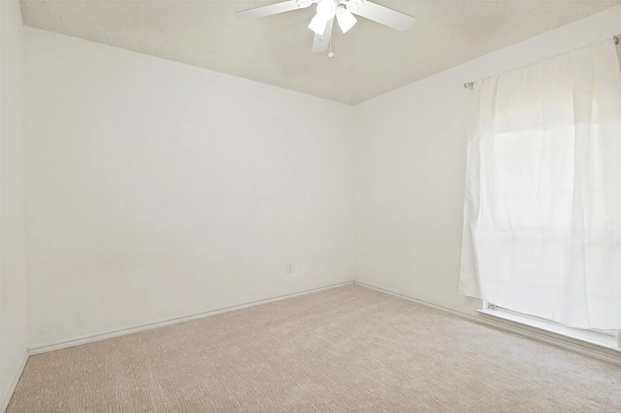 Neutral tone wall finishes, carpeting, and a ceiling fan