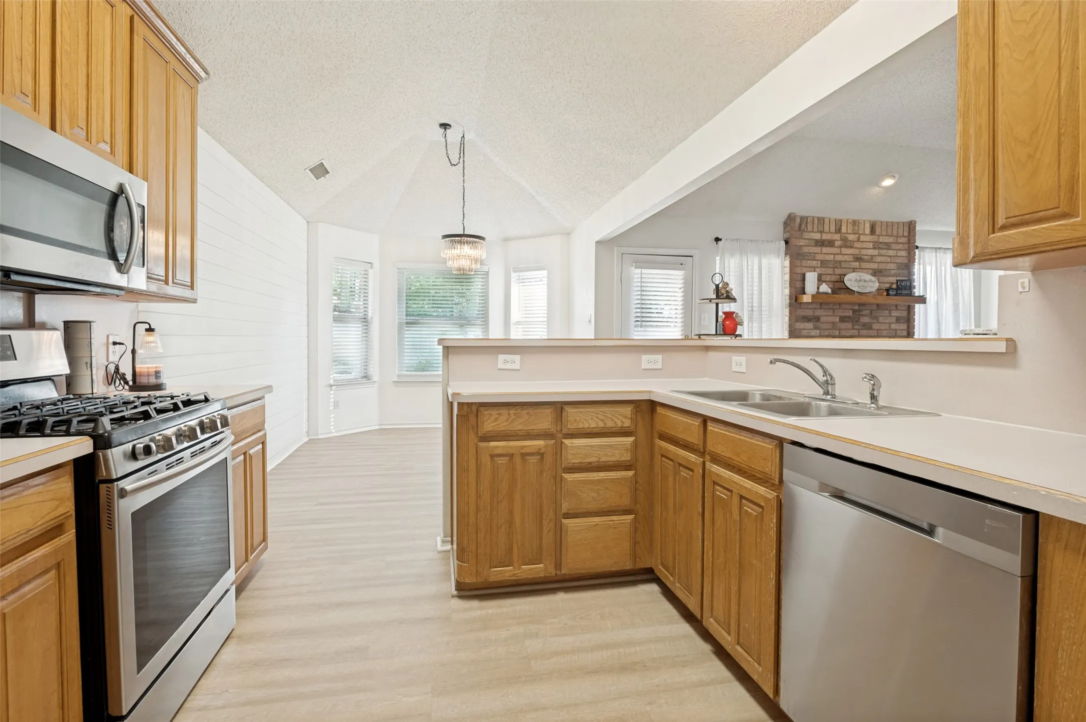Kitchen featuring wood-finish cabinetry, stainless steel appliances, and a double basin sink