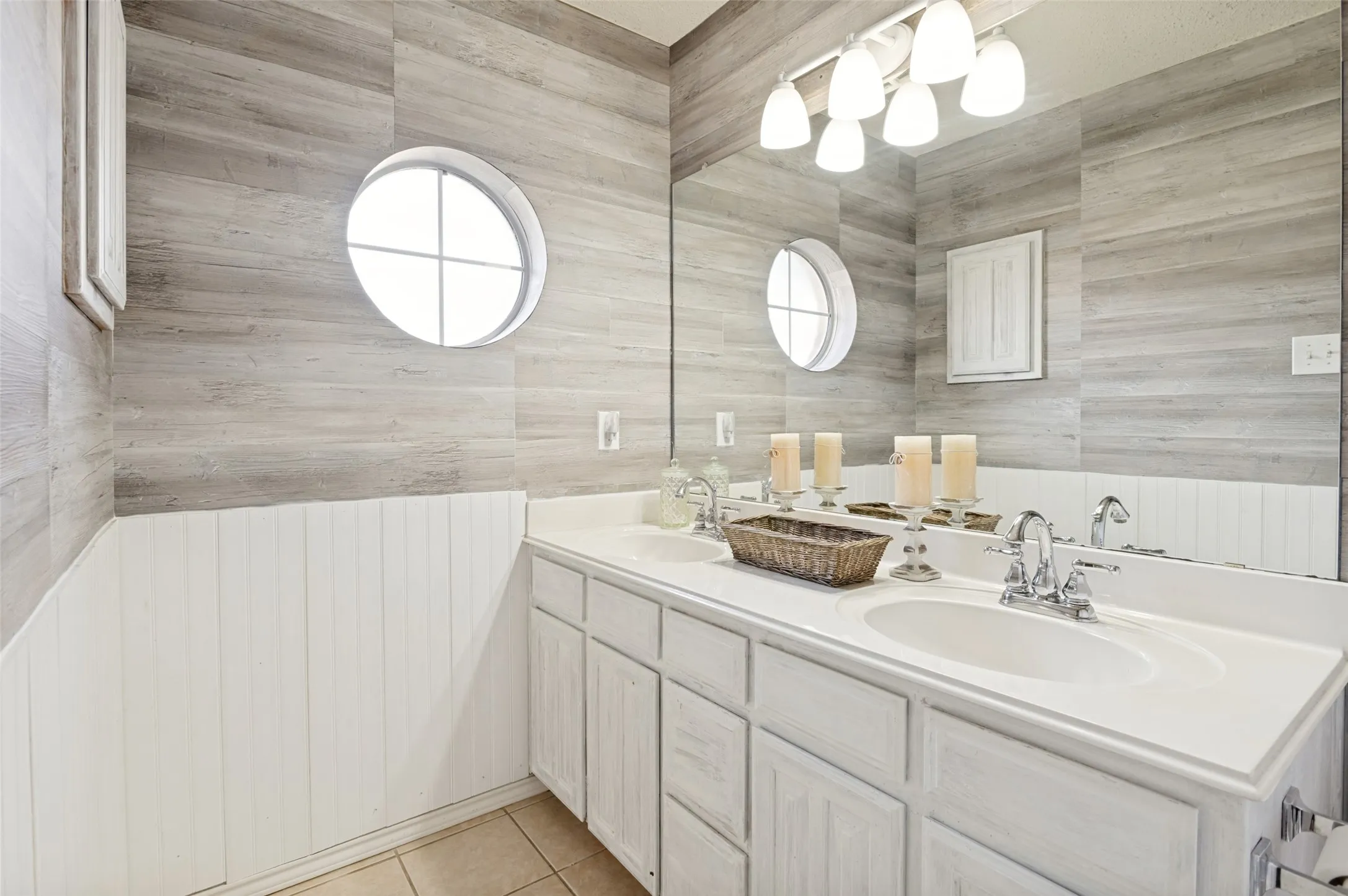 Dual basin vanity with chrome fixtures and white cabinetry, featuring a large wall-mounted mirror